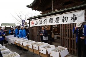 尾道浜問屋初市と書かれた幕の前であいさつする組合理事長の写真