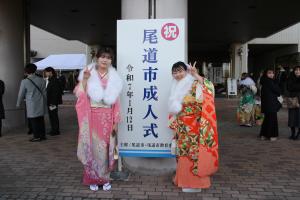 成人式の看板の前で記念撮影する振袖の2人