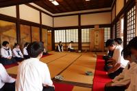 お茶室に制服姿の生徒が並んで座っている写真